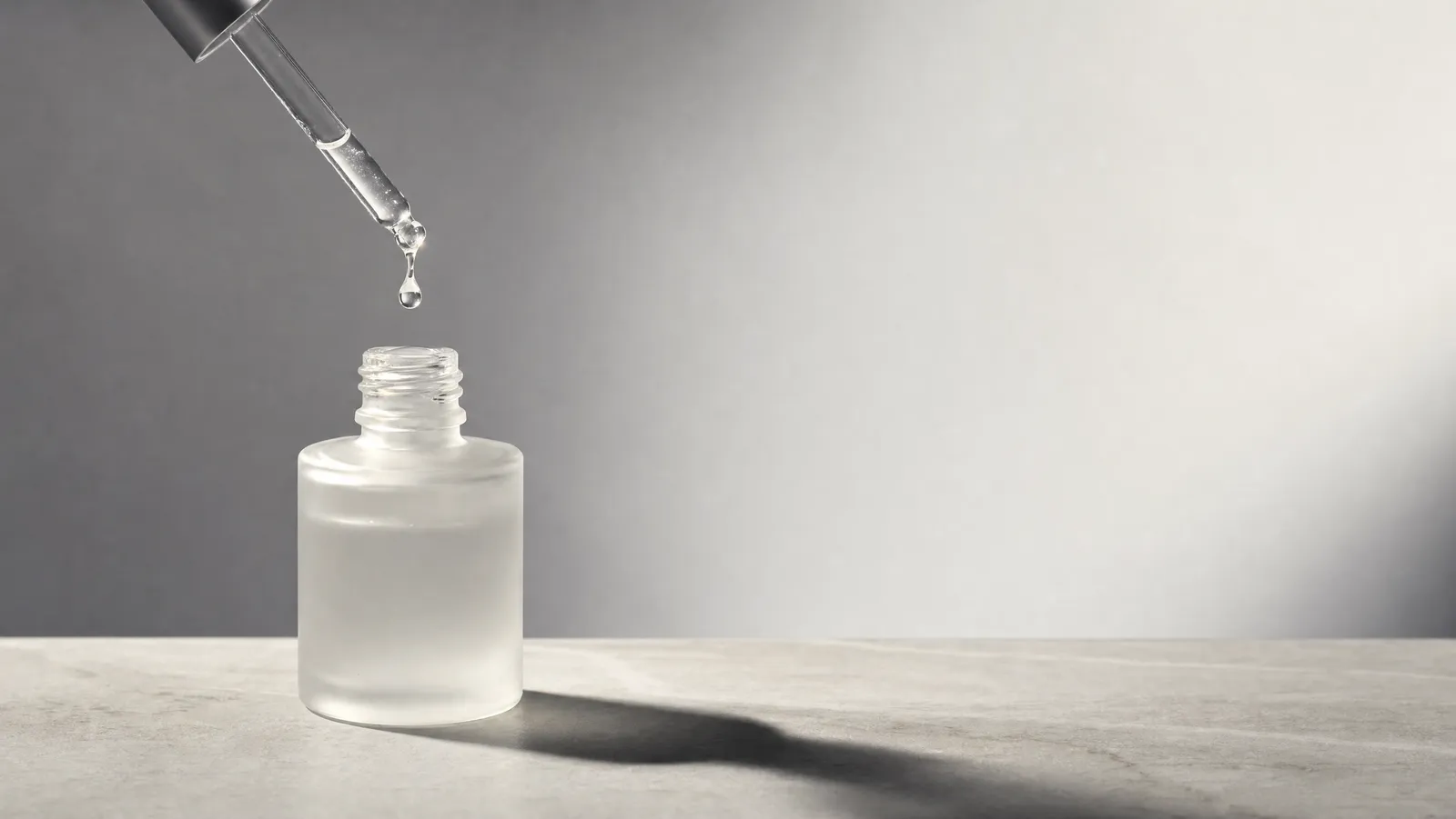 A frosted-glass dropper bottle with a glossy bead of snail mucin essence